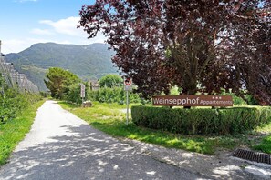 A sign for Weinsepphof Apartments with a road leading to it, surrounded by greenery and a mountain in the background.