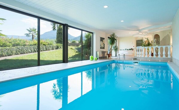 A swimming pool with a view of mountains, a balcony with a railing, and a potted plant.