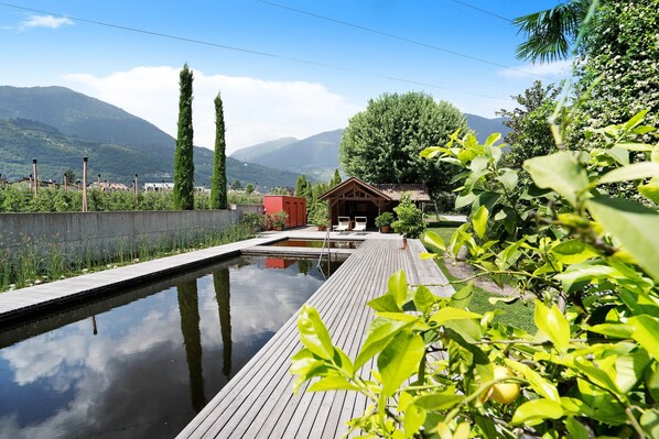 A wooden deck leading to a pool with a mountain backdrop.