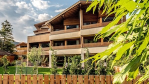 A multi-story building with balconies, a wooden fence, and a grassy yard.