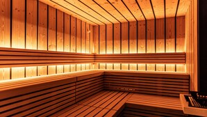 Un sauna avec des bancs en bois et des murs à lattes, éclairé par un éclairage chaleureux.