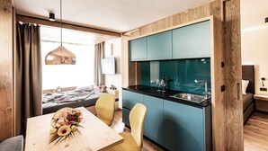 Une pièce de taille modeste comprenant une table à manger, des chaises, un coin cuisine et un lit.