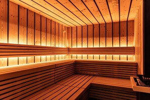 A sauna with wooden benches and slatted walls, illuminated by warm lighting. - Apartment "Mysciliar Tree II" with Mountain View, Wi-Fi, Garden, Terrace & Balcony (Seis am Schlern / Südtirol)