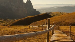 Een houten pad dat naar een bergachtig landschap leidt, met een opvallende rotsformatie.