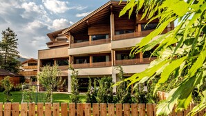 A multi-story building with balconies, a wooden fence, and a grassy yard.