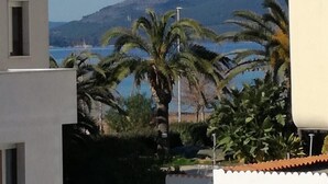 A modern building with a view of a mountain and a body of water. - Apartment San Giovanni Lido Close to the Beach with Sea View & Balcony (Alghero)