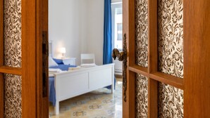 A bedroom with a bed, bedside table, and curtains. - Apartment San Giovanni Lido Close to the Beach with Sea View & Balcony (Alghero)
