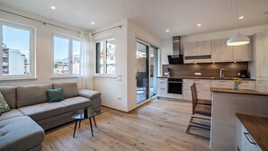 Eine moderne Wohnung mit Wohnbereich, Küchenzeile und großen Fenstern mit Blick auf die Stadt.