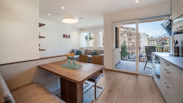 Eine moderne Wohnung mit Essbereich, Küche und einem Balkon mit Blick auf die Stadt.
