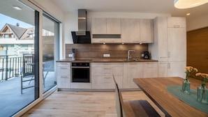 Eine moderne Küche mit Einbauofen, Kaffeemaschine und Essbereich mit Holztisch und Stühlen.