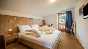 A bedroom with a wooden bed, bedside table, and a view of a balcony. - Holiday Apartment "Residenz Condor Schlern" with Mountain View, Sauna & Garden (Meransen)