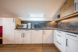 A modern kitchen with a microwave, coffee maker, and wooden cabinets.