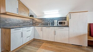Een moderne keuken met houten kastjes, een marmeren spatwand en een ingebouwde magnetron.