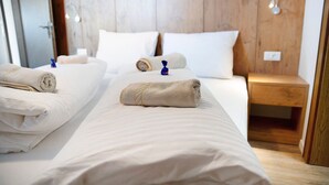 Una camera d'albergo con due letti, una testiera in legno, comodini e un tavolino da notte.