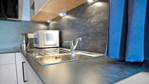 Una cucina moderna con lavello in acciaio inossidabile, forno a microonde e piano di lavoro in legno.