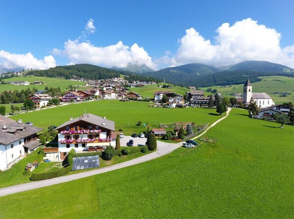 Un pittoresco borgo rurale con case tradizionali, una chiesa e una vista panoramica sulle montagne circostanti.