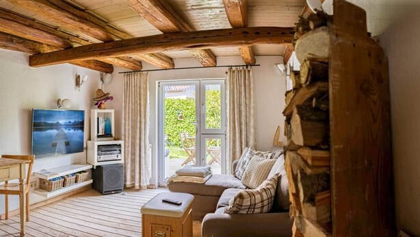 Una sala de estar acogedora con techo de madera, un sofá, un televisor y una chimenea.