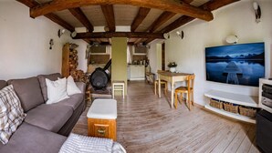 Una sala de estar acogedora con un sofá, una mesa de centro de madera, un televisor y un comedor con una mesa y sillas.