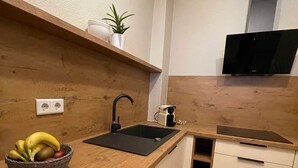 Una cocina con mostrador de madera, un lavamanos negro y una cesta de fruta.