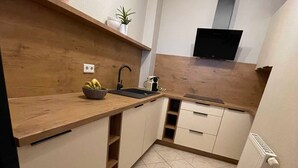Una cocina compacta con encimeras de madera, un lavamanos integrado y piso de baldosas.