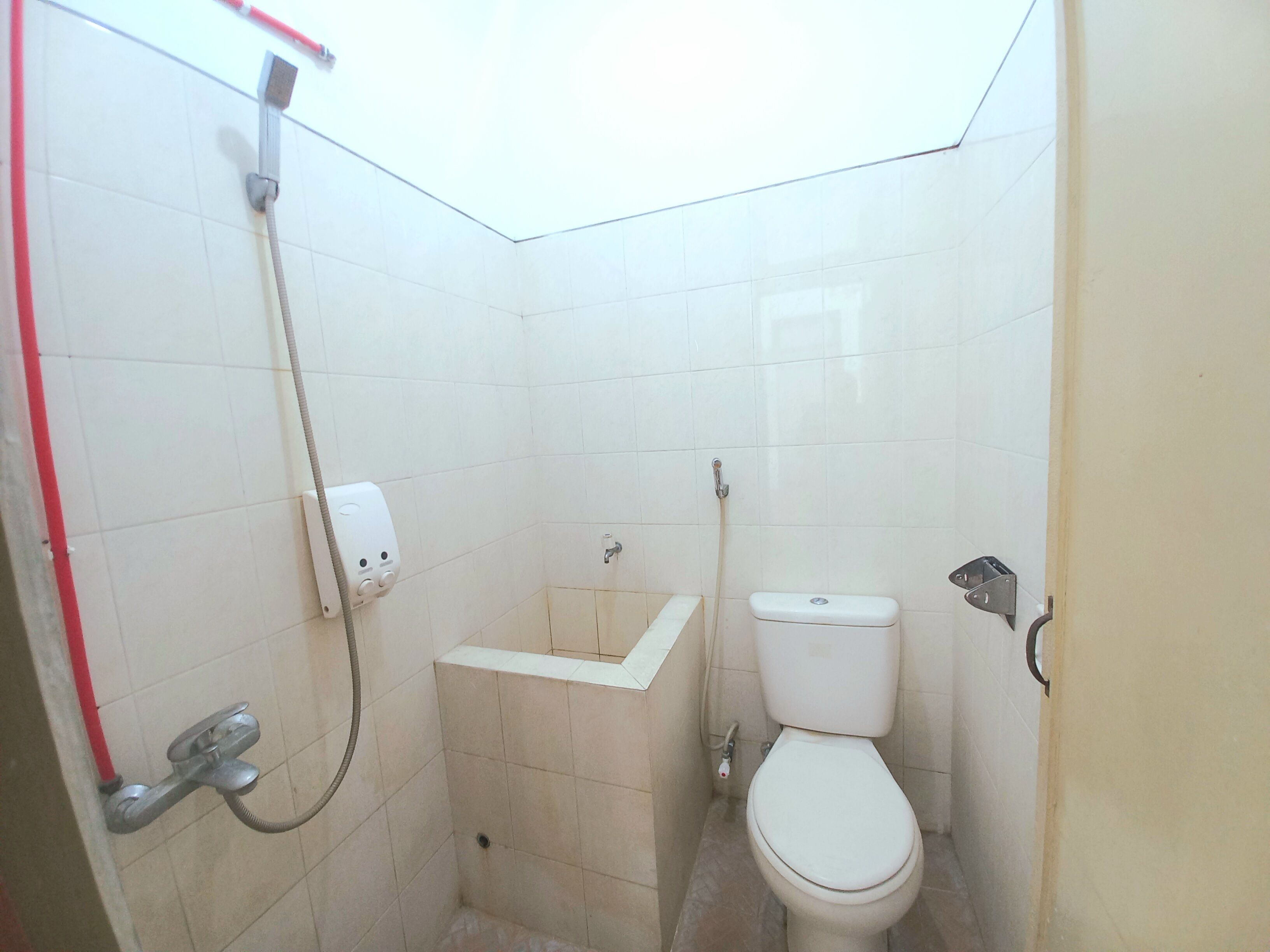 A small, tiled bathroom with a toilet, a sink, and a shower.