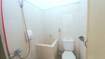 A small, tiled bathroom with a toilet, a sink, and a shower.
