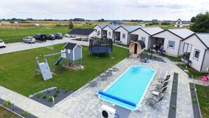 A residential area with a swimming pool, trampoline, and play structures.