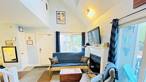 A cozy living room with a sofa, a television, and a fireplace. - Cozy Studio Loft with 2 Baths Next to the Slopes (The Blue Mountains)
