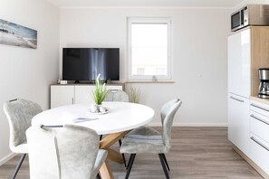 A modern kitchen with a microwave, a coffee machine, and a white refrigerator.