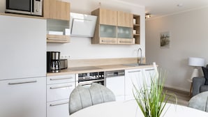 Een moderne keuken met witte kasten, een inbouwoven en een koffiezetapparaat.