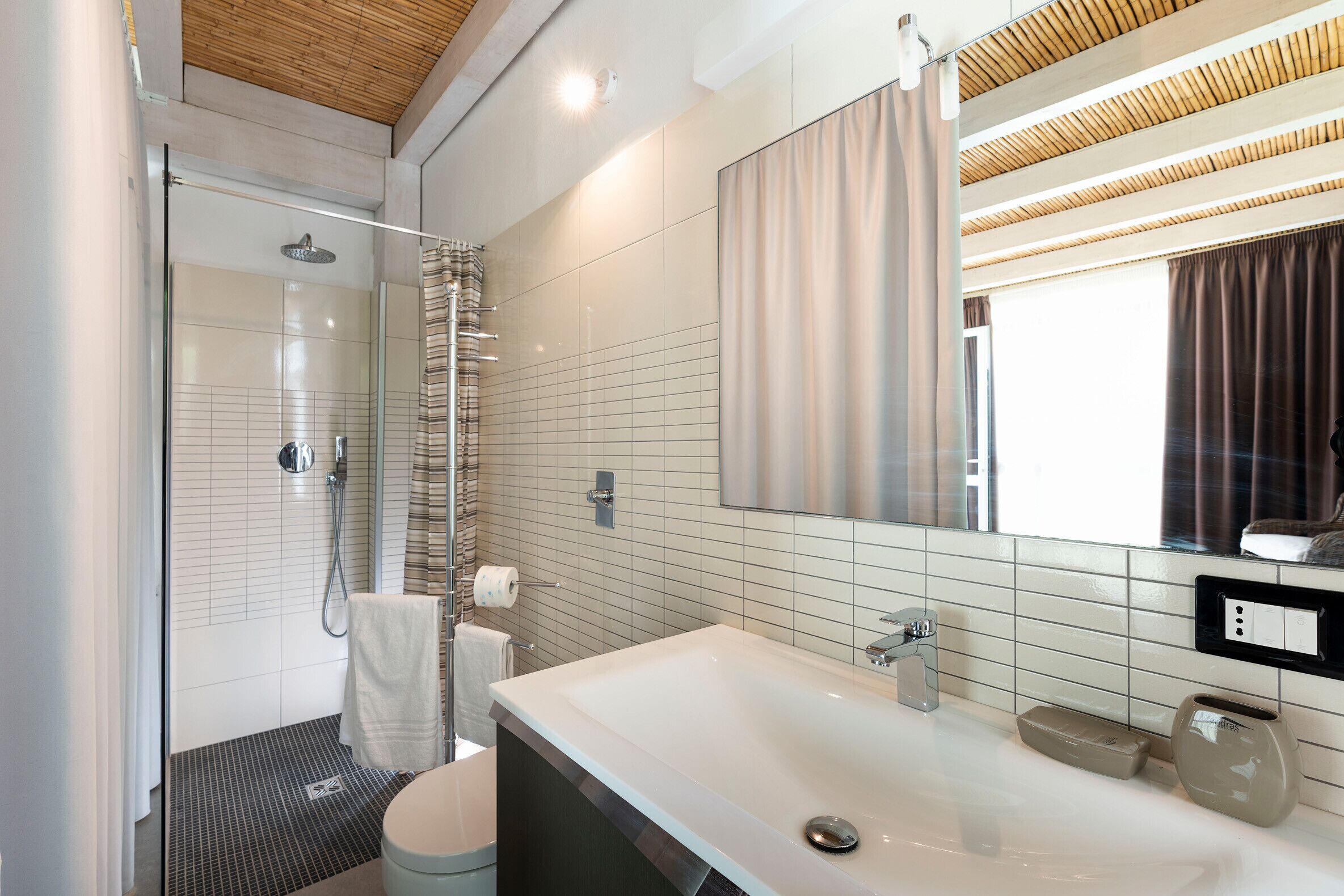 Un baño moderno con cabina de ducha de vidrio, un espejo grande y un lavabo con encimera.