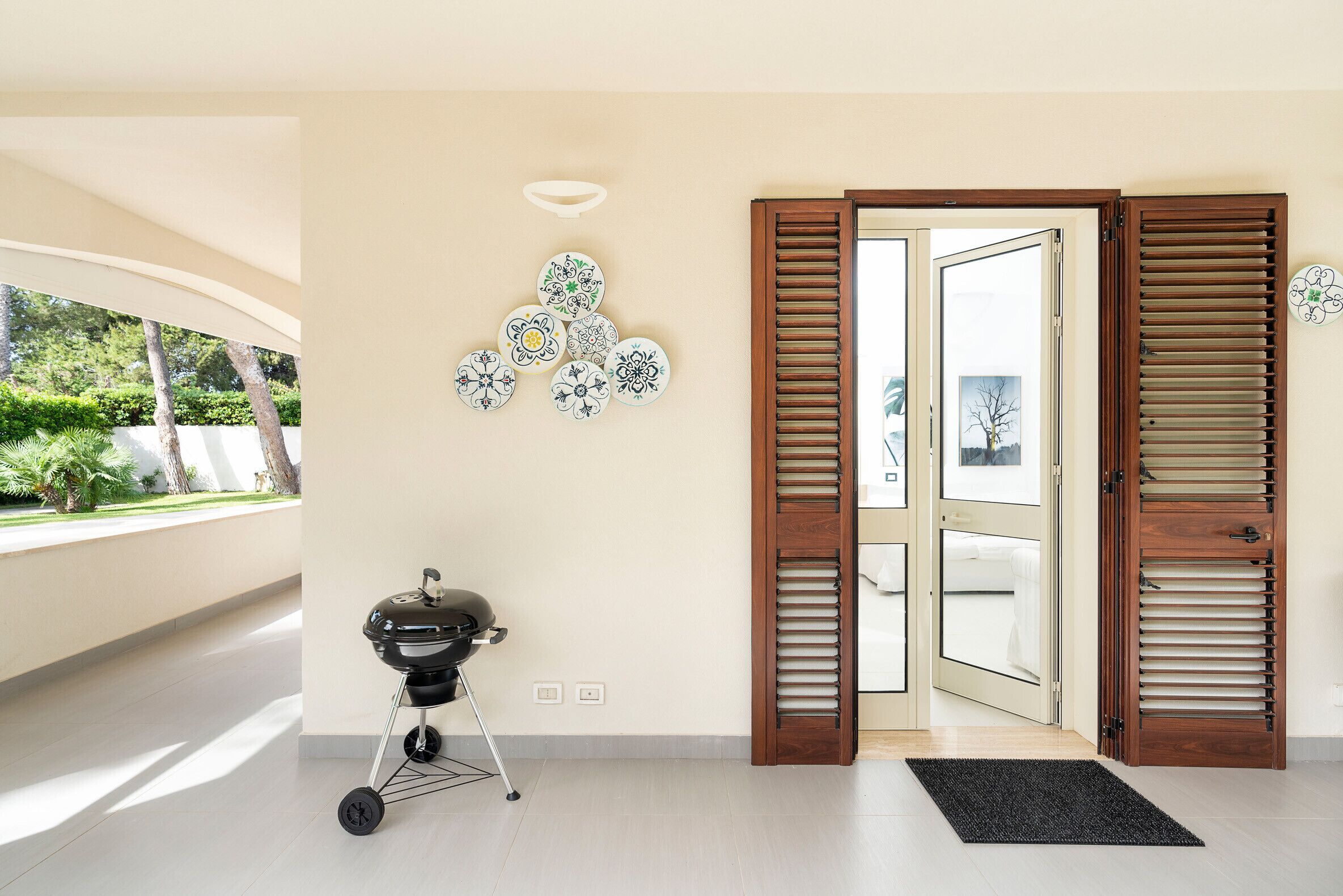 Ein modernes Interieur mit Grill, einer Tür mit Fensterläden und dekorativen Tellern an der Wand.