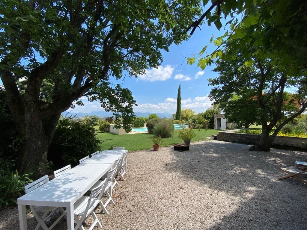 A garden with a white table and chairs, a pool, and a view of the mountains.