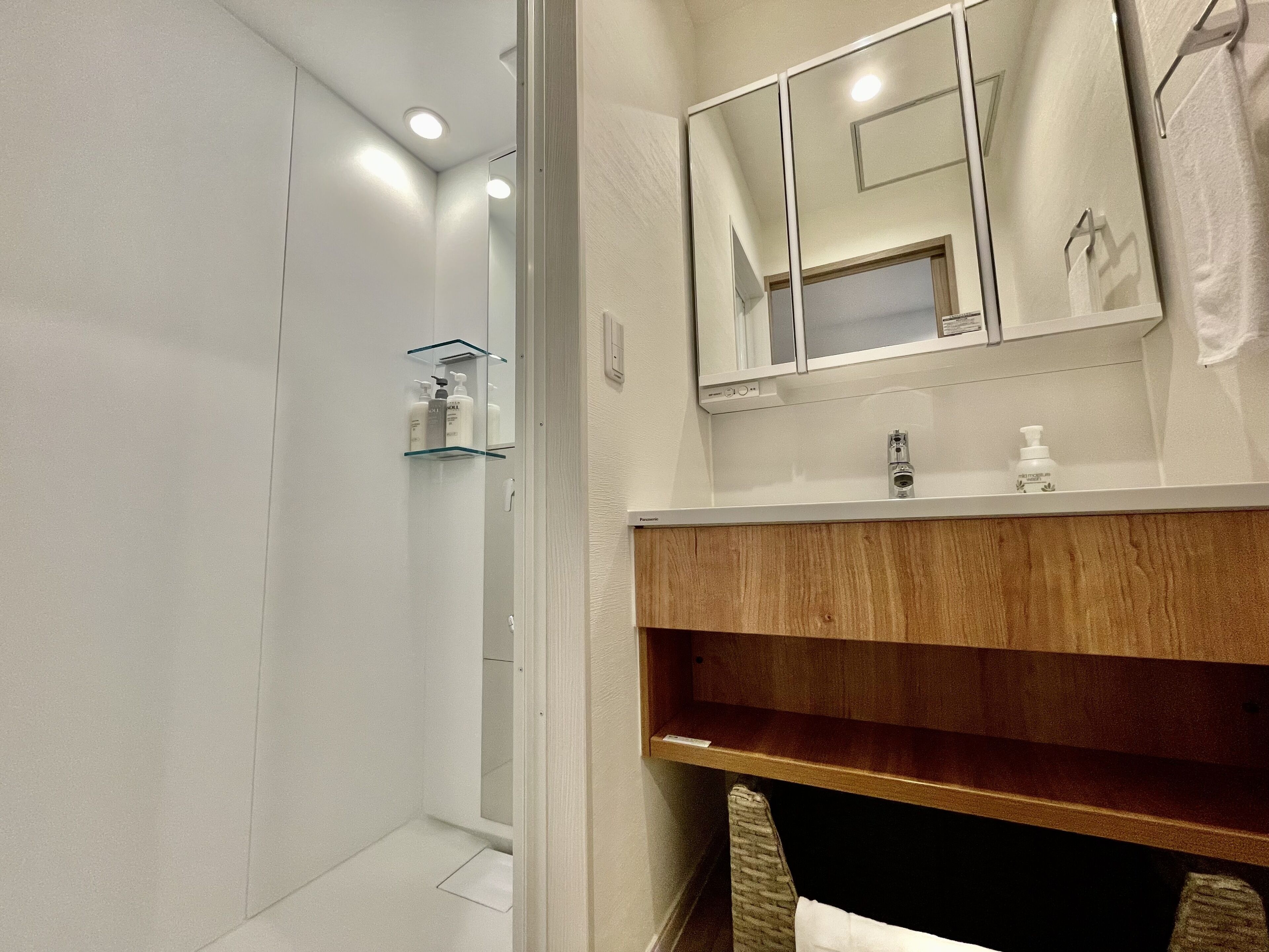 A modern bathroom with a wooden vanity, a mirror, and a glass shower enclosure.
