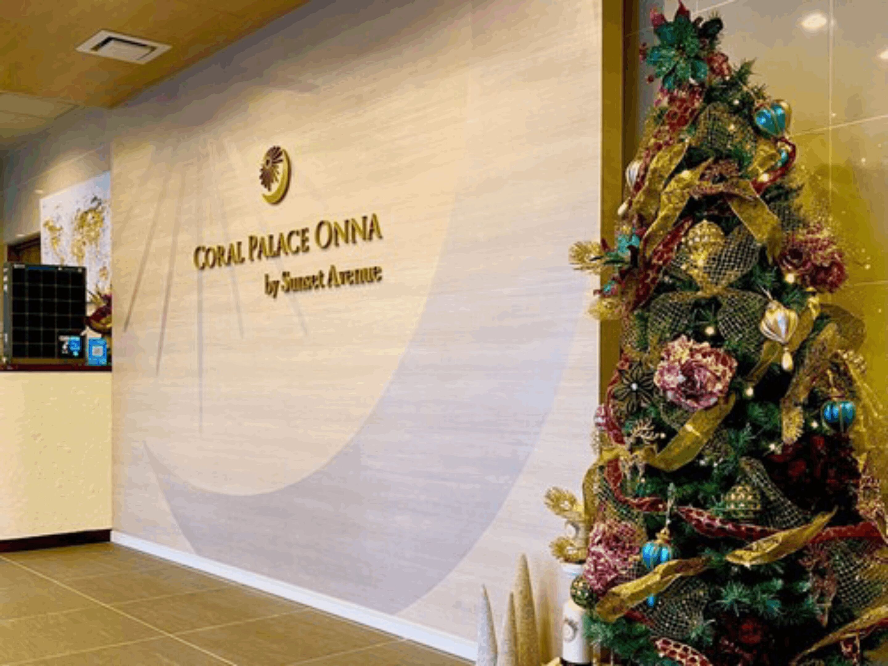 Interior de un hotel con un letrero que dice "CORAL PALACE ONNA by Sunset Avenue".