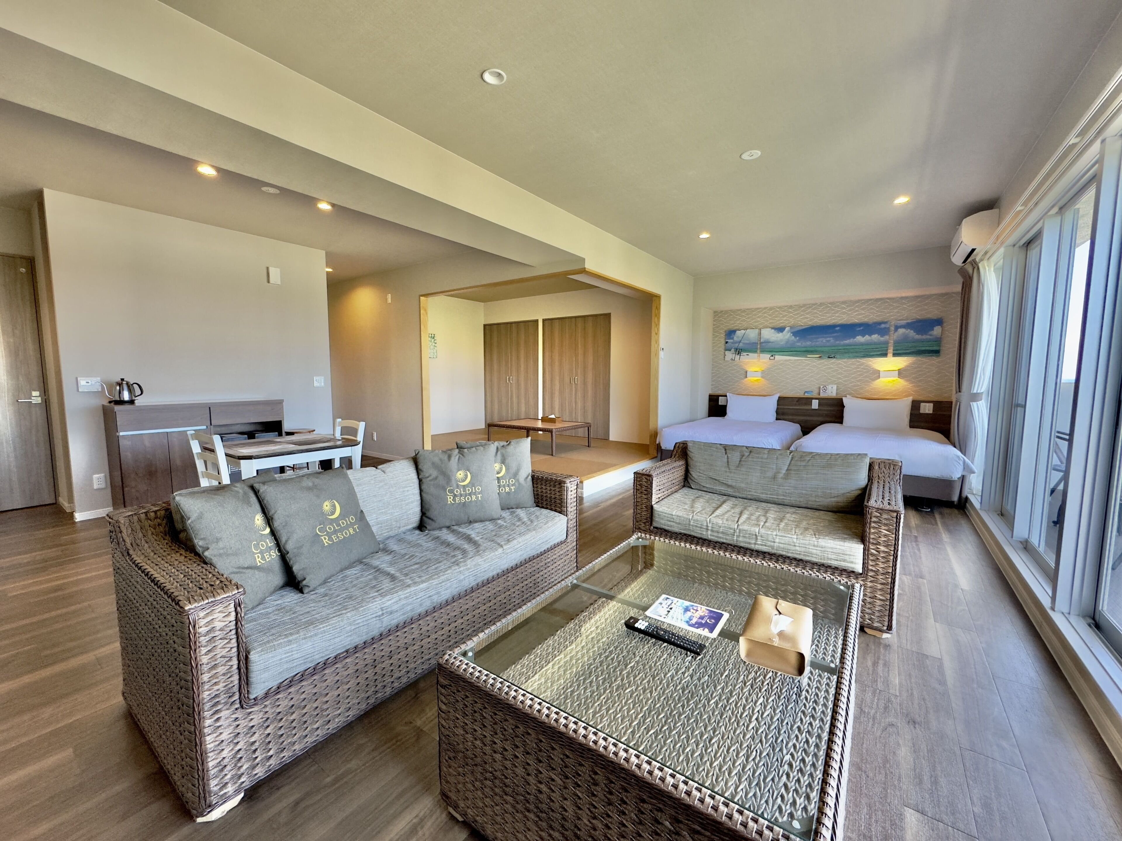 A spacious living area with a sofa set, a coffee table, and a bed with a view.
