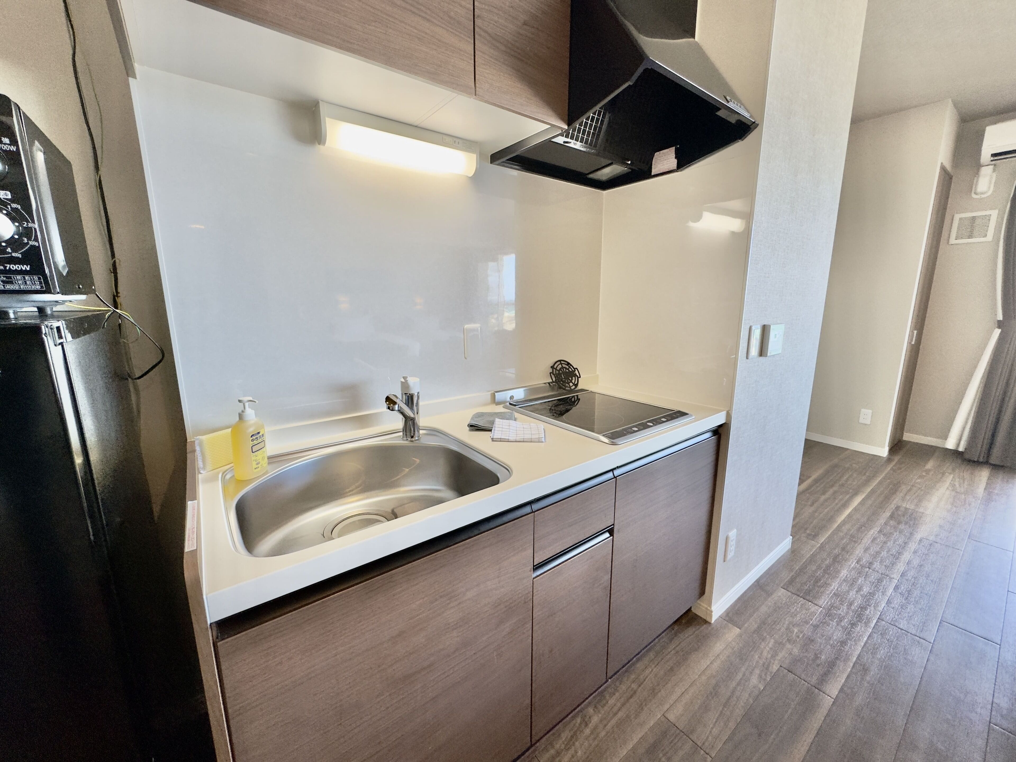 A modern kitchen with a stainless steel sink, a built-in stove, and wooden cabinets.