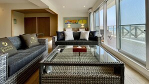 A modern living room with a sofa set, a glass coffee table, and a view of the sea. - Coral Palace Onna by Sunset Avenue (Onna)