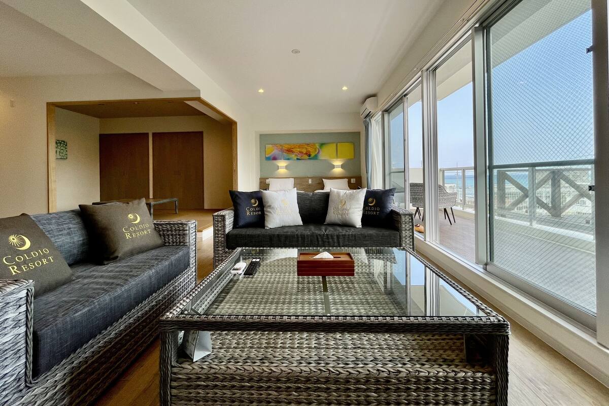 Un salon moderne avec un ensemble de canapés, une table basse en verre et une vue sur la mer.