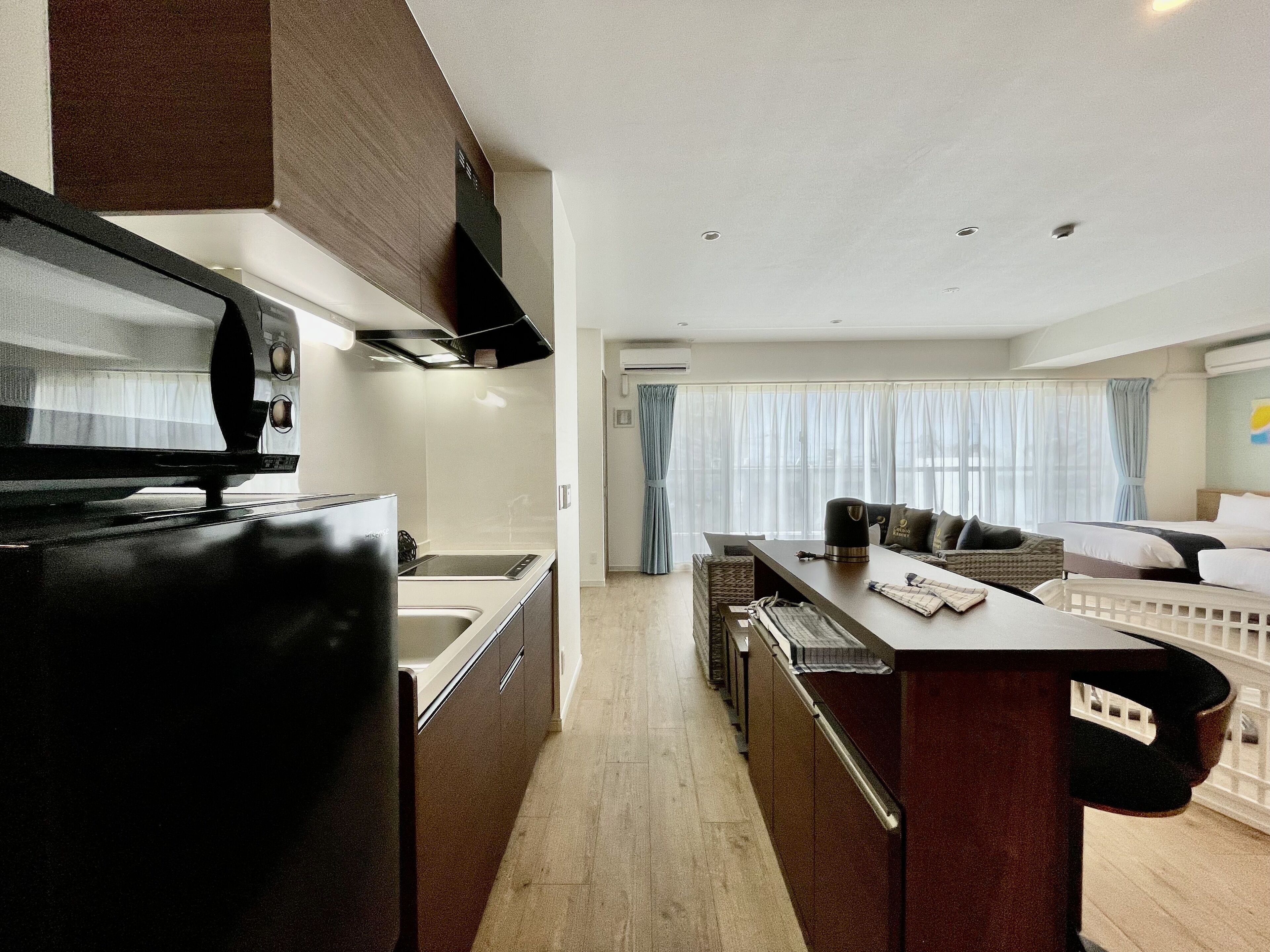 A modern kitchen with a black refrigerator, a dining area with a table and chairs, and a living area with a sofa and a bed.