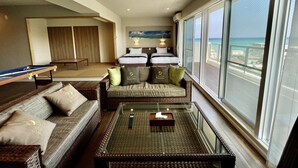 A hotel room with a balcony, a sofa, a coffee table, and a pool table. - Coral Palace Onna by Sunset Avenue (Onna)
