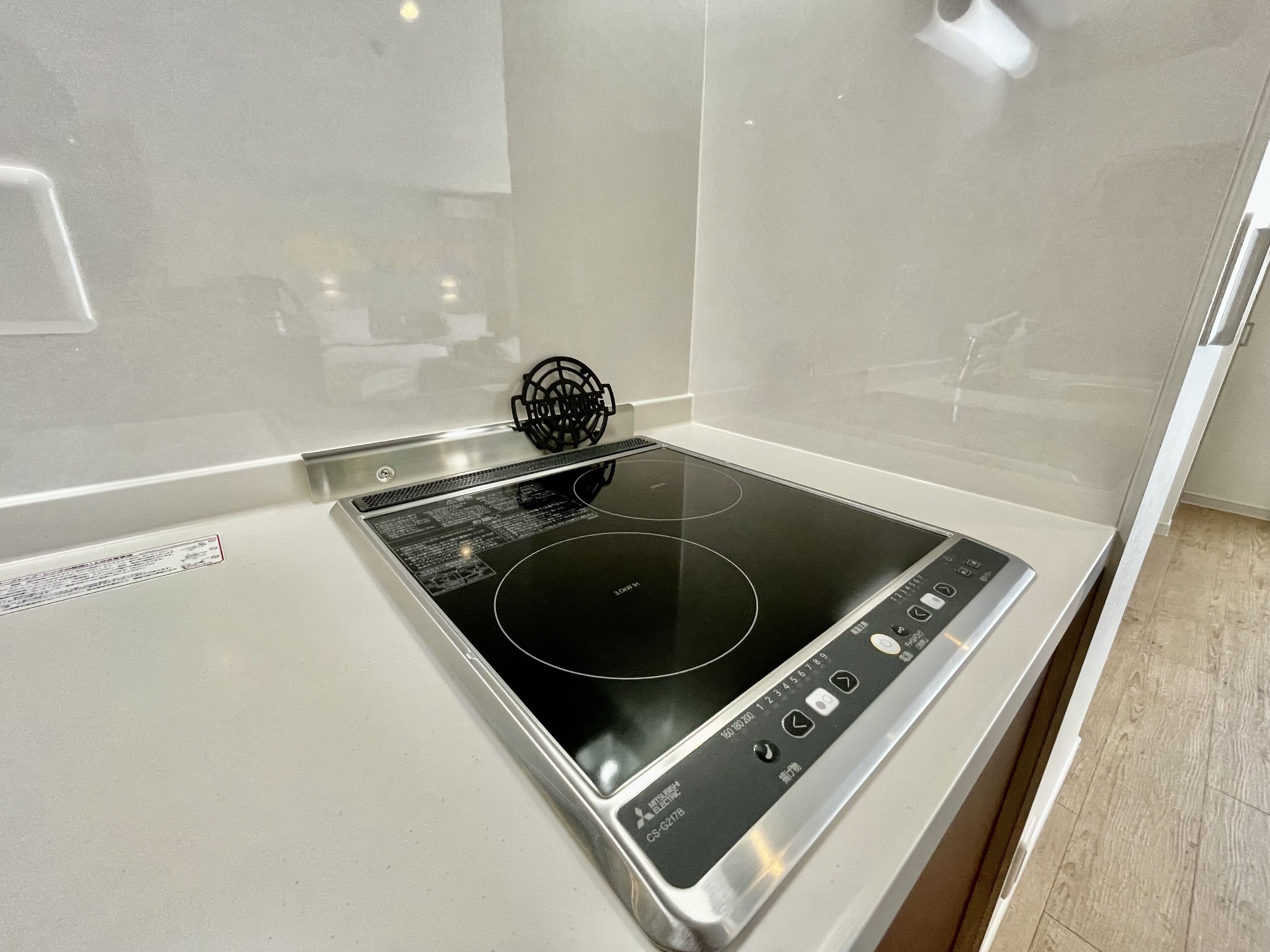 A kitchen with a built-in induction cooktop and a stainless steel backsplash.