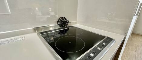 A kitchen with a built-in induction cooktop and a stainless steel backsplash.