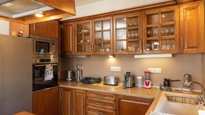 A kitchen with wooden cabinets, a stainless steel refrigerator, a microwave, a toaster, and a coffee maker. - Villa Parisi Naxos Deluxe 2 (Ναξος Αγκίδια)