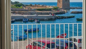 Un balcon offrant une vue sur une zone côtière, avec notamment une tour et des bateaux.