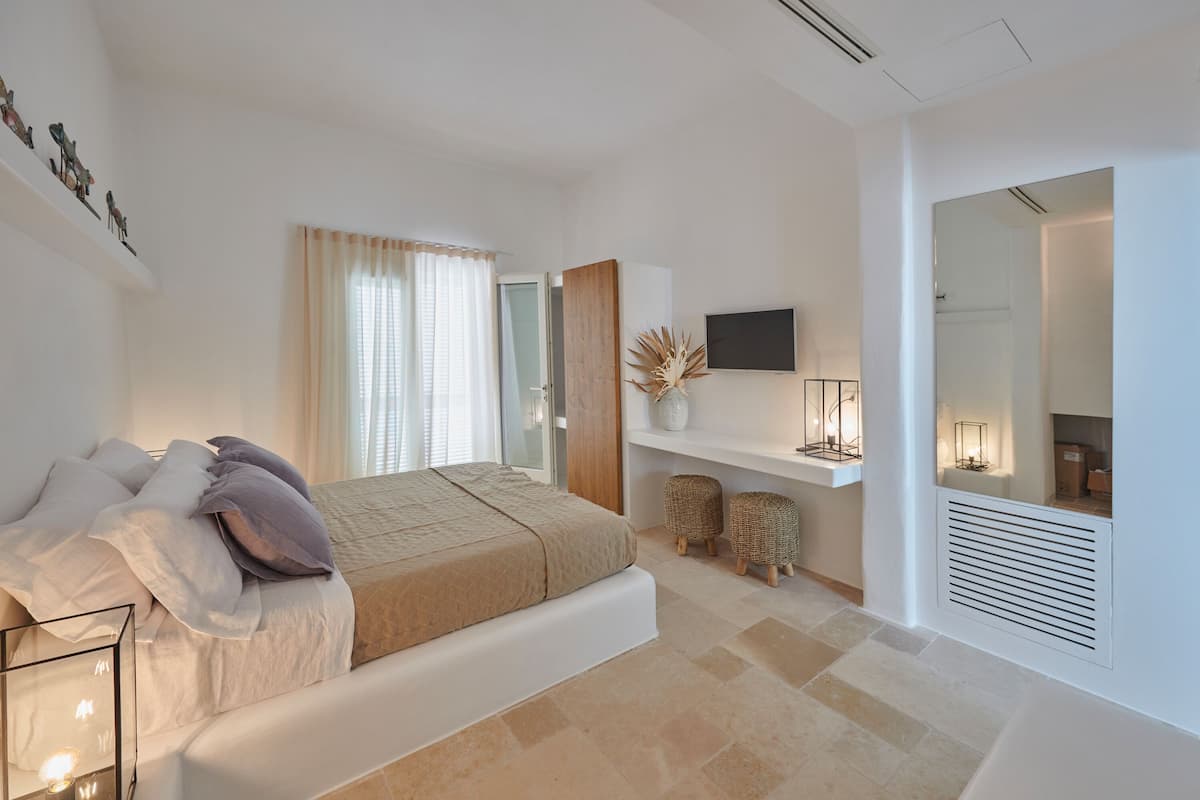 A modern bedroom with a bed, bedside tables, a TV, and a mirror.