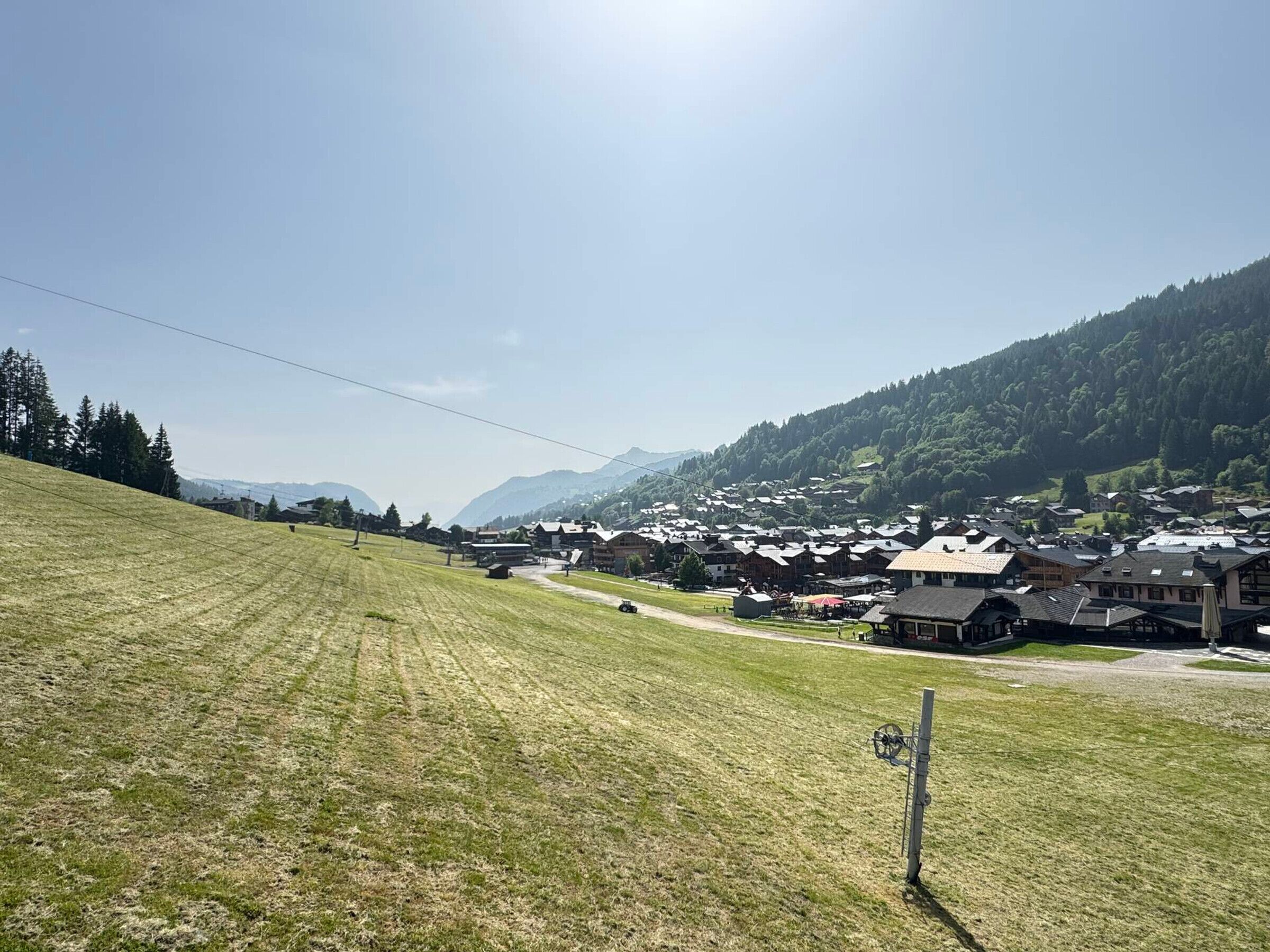 A rural village with traditional buildings, a clear sky, and a grassy field.