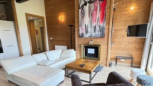A modern living room with a white sectional sofa, a dark armchair, a wooden coffee table, and a painting on the wall.
