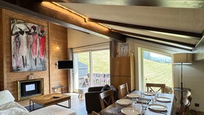 A modern living room with a sofa, a dining table set for four, and a painting on the wall.