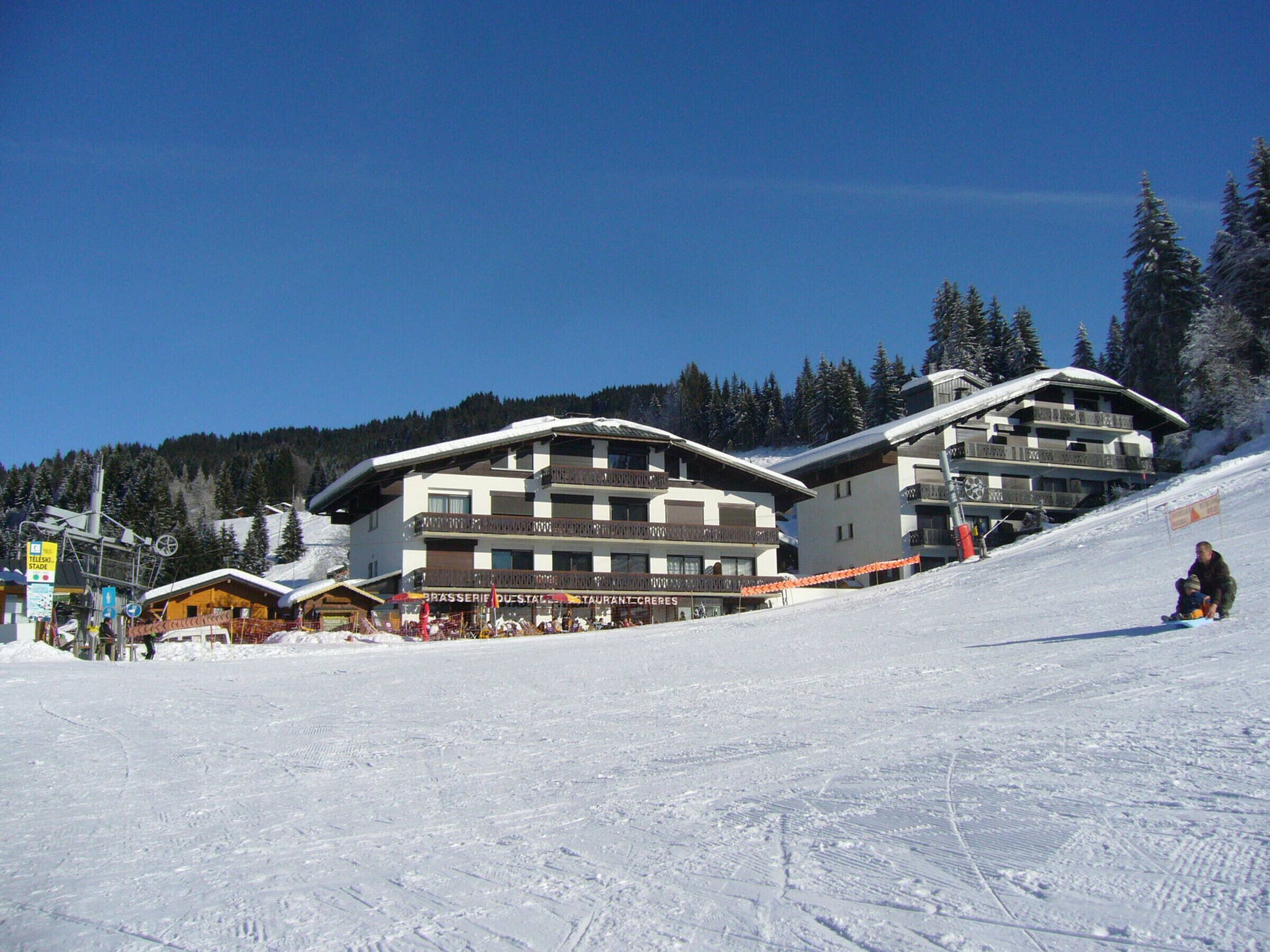 A ski resort with multiple buildings, including a restaurant and a hotel with balconies.